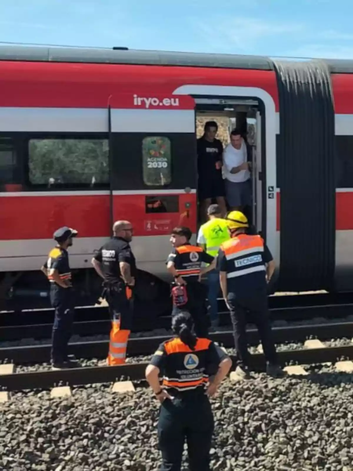 Varias personas de protección civil y emergencias ayudan a pasajeros a bajar de un tren detenido en las vías Varias personas de protección civil y emergencias ayudan a pasajeros a bajar de un tren detenido en las vías