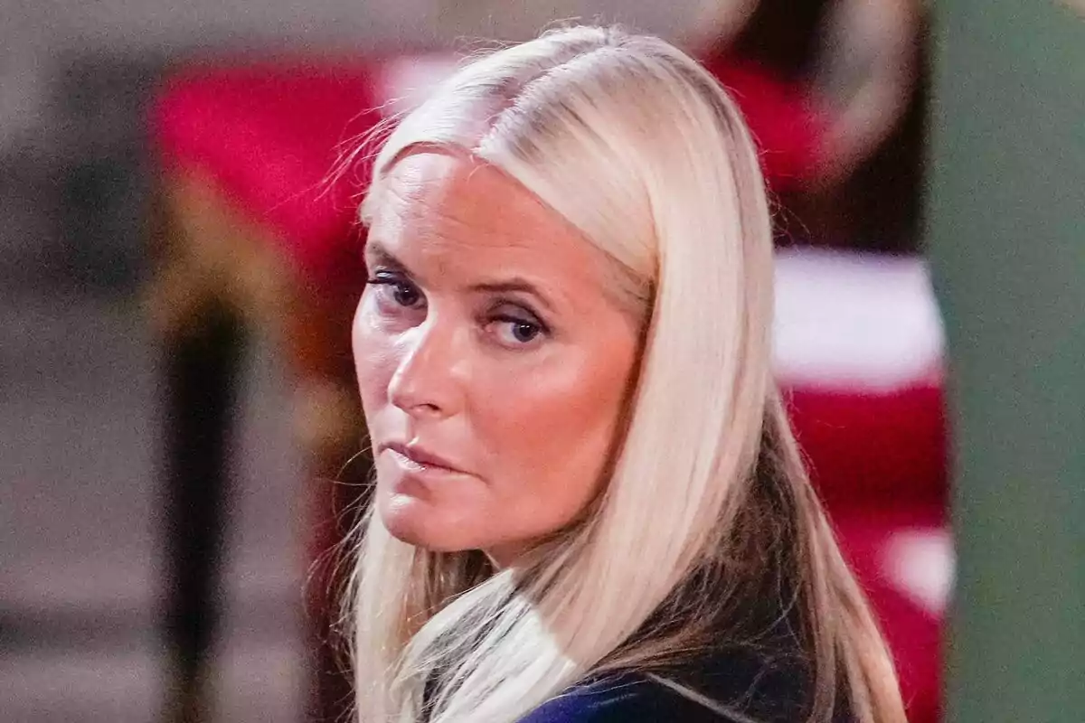 Mujer de cabello rubio lacio mirando hacia un lado con expresión seria