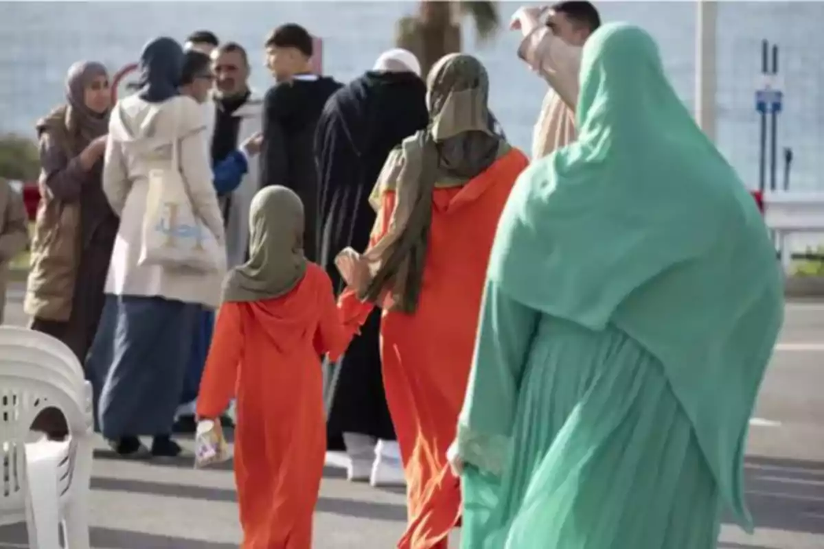 Varias personas con vestimenta tradicional caminan y conversan en una calle durante el día Varias personas con vestimenta tradicional caminan y conversan en una calle durante el día