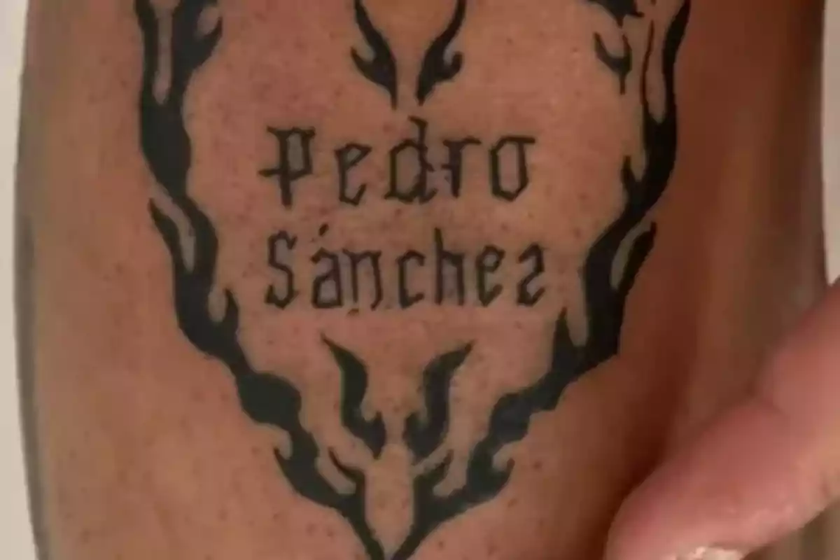 Tatuaje en la piel con el nombre Pedro Sánchez rodeado de un diseño de llamas negras Tatuaje en la piel con el nombre Pedro Sánchez rodeado de un diseño de llamas negras