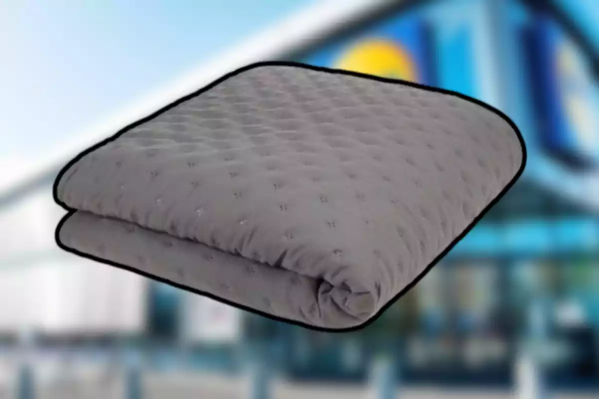 Manta gris doblada con textura acolchada sobre un fondo desenfocado de una tienda Manta gris doblada con textura acolchada sobre un fondo desenfocado de una tienda