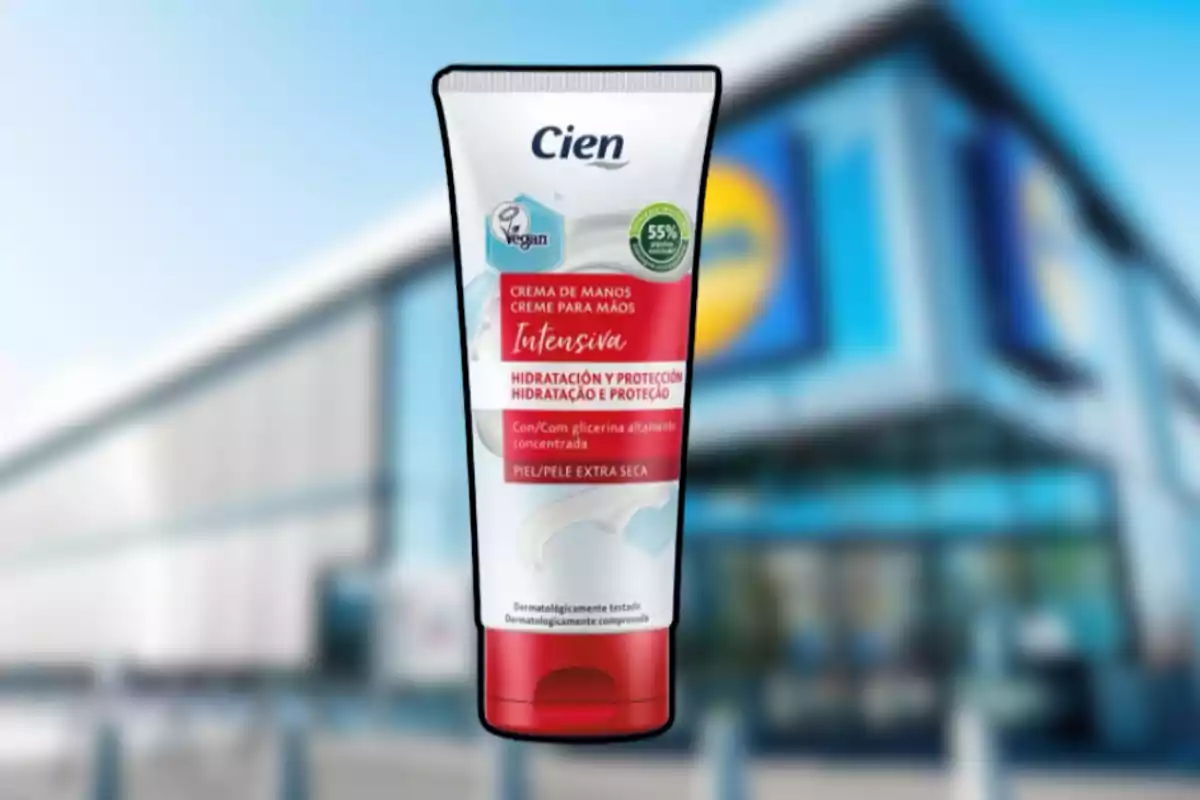 Crema de manos Cien Intensiva con envase blanco y rojo frente a una tienda con fachada moderna desenfocada Crema de manos Cien Intensiva con envase blanco y rojo frente a una tienda con fachada moderna desenfocada