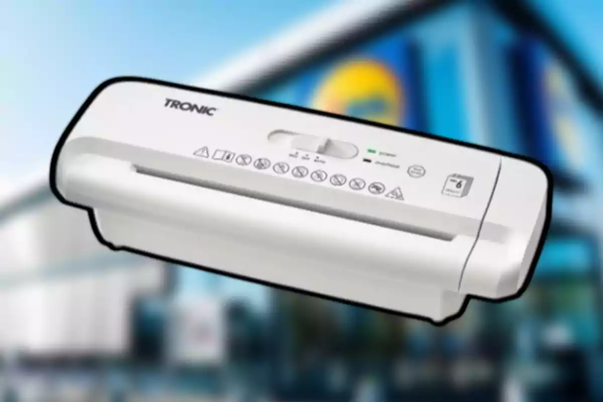 Destructora de papel blanca marca Tronic sobre un fondo desenfocado de una tienda Destructora de papel blanca marca Tronic sobre un fondo desenfocado de una tienda