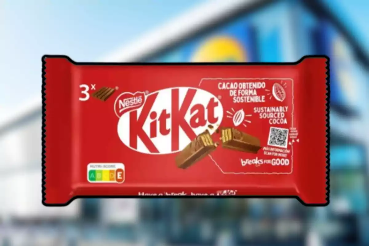 Empaque de chocolate Kit Kat de Nestlé en color rojo con información sobre cacao sostenible y un fondo desenfocado de una tienda Empaque de chocolate Kit Kat de Nestlé en color rojo con información sobre cacao sostenible y un fondo desenfocado de una tienda