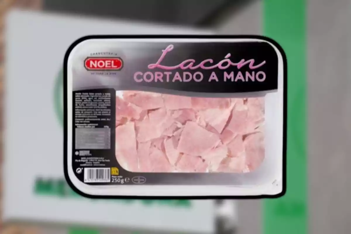 Envase de lacón cortado a mano de la marca Noel con trozos de carne rosada visibles a través del plástico transparente. Envase de lacón cortado a mano de la marca Noel con trozos de carne rosada visibles a través del plástico transparente.