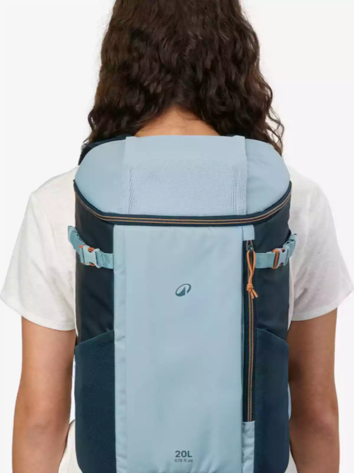 Persona de espaldas con cabello rizado usando una mochila azul claro y azul oscuro sobre una camiseta blanca Persona de espaldas con cabello rizado usando una mochila azul claro y azul oscuro sobre una camiseta blanca