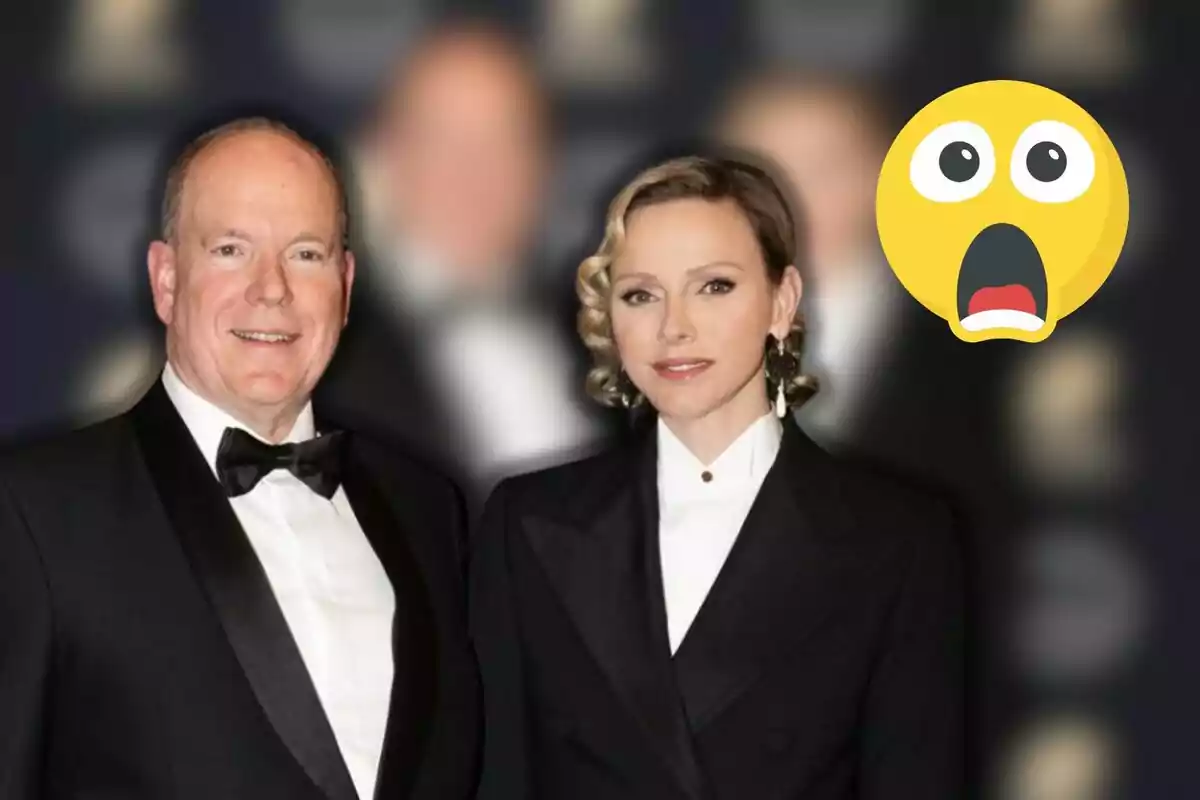 Albert and Charlene of Monaco, elegantly dressed, pose for the camera with a blurred background and a large surprised emoji on the right.