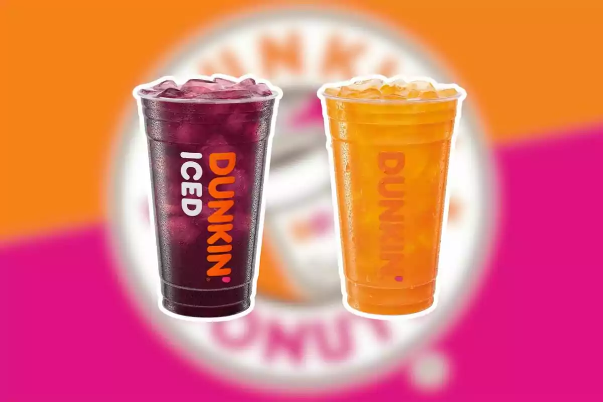 Dos vasos grandes de bebidas frías de Dunkin, uno de color morado y otro naranja, sobre un fondo con los colores y el logo de la marca desenfocados. Dos vasos grandes de bebidas frías de Dunkin, uno de color morado y otro naranja, sobre un fondo con los colores y el logo de la marca desenfocados.