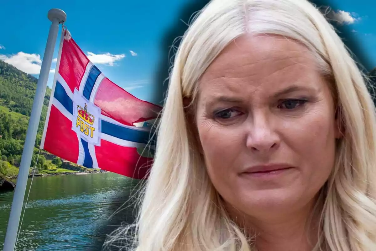 Mette-Marit de expresión seria en primer plano con una bandera de Noruega ondeando al fondo junto a un paisaje de lago y montañas
