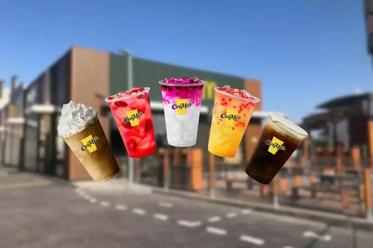 Cinco bebidas coloridas de la marca CosMc’s flotan frente a un edificio moderno con cielo despejado. Cinco bebidas coloridas de la marca CosMc’s flotan frente a un edificio moderno con cielo despejado.