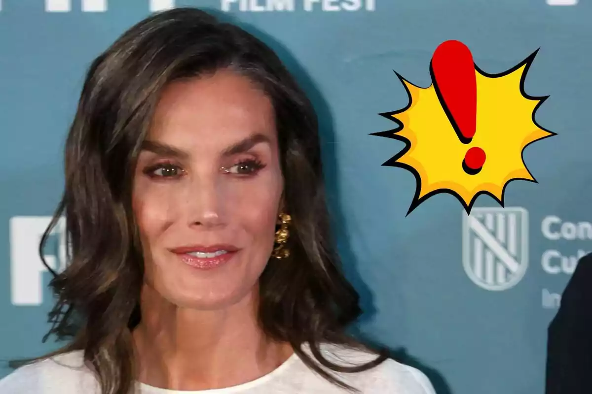 La reina Letizia con fondo azul y un dibujo de signo de exclamación amarillo y rojo a su lado