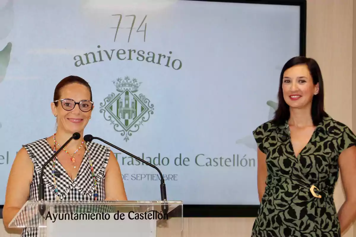 Dos mujeres posan sonrientes en un evento del Ayuntamiento de Castellón con un cartel de aniversario de fondo Dos mujeres posan sonrientes en un evento del Ayuntamiento de Castellón con un cartel de aniversario de fondo