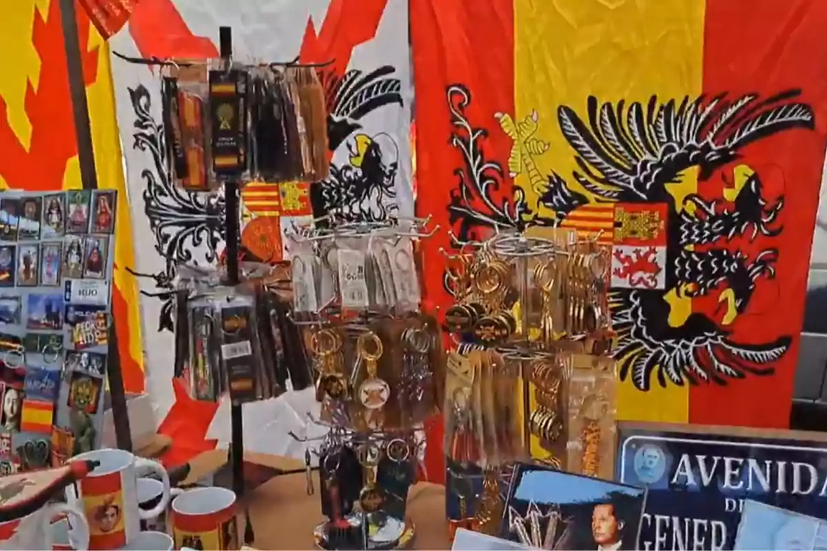 Puesto de souvenirs con llaveros, tazas, imanes y banderas con el escudo de España y colores rojo y amarillo de fondo Puesto de souvenirs con llaveros, tazas, imanes y banderas con el escudo de España y colores rojo y amarillo de fondo