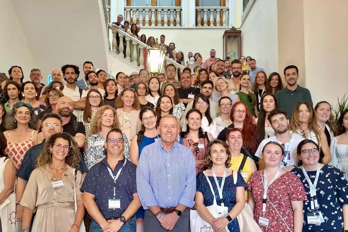 Un gran grupo de personas sonríe y posa para una foto en una escalera dentro de un edificio elegante
