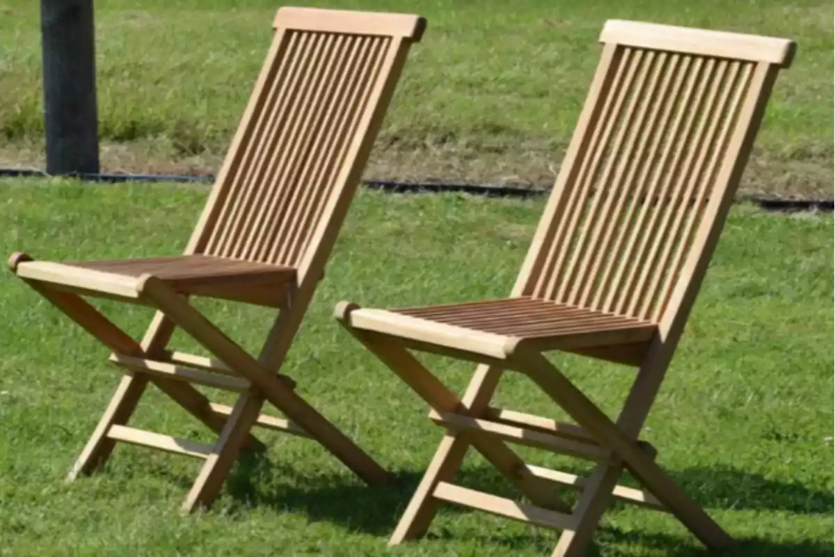 Dos sillas de madera plegables están colocadas sobre césped verde en un espacio al aire libre Dos sillas de madera plegables están colocadas sobre césped verde en un espacio al aire libre