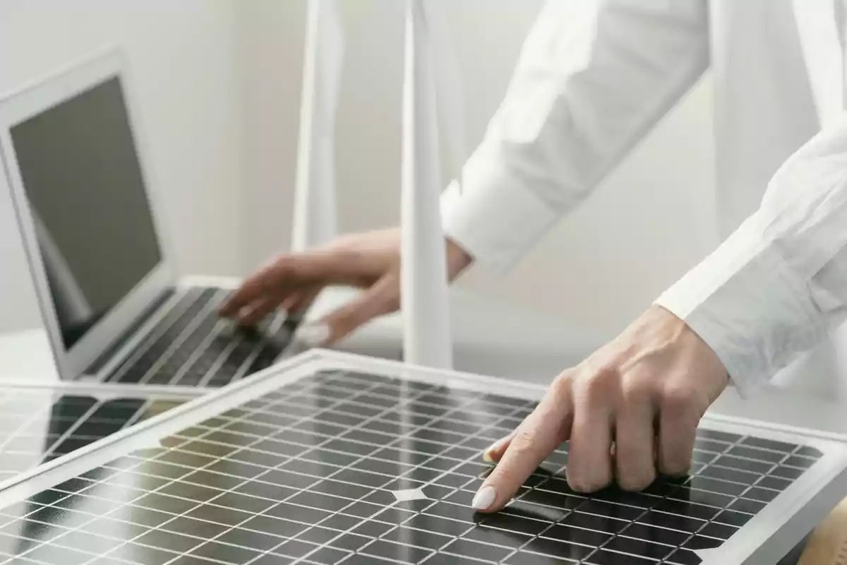 Persona trabajando en una computadora portátil mientras toca un panel solar