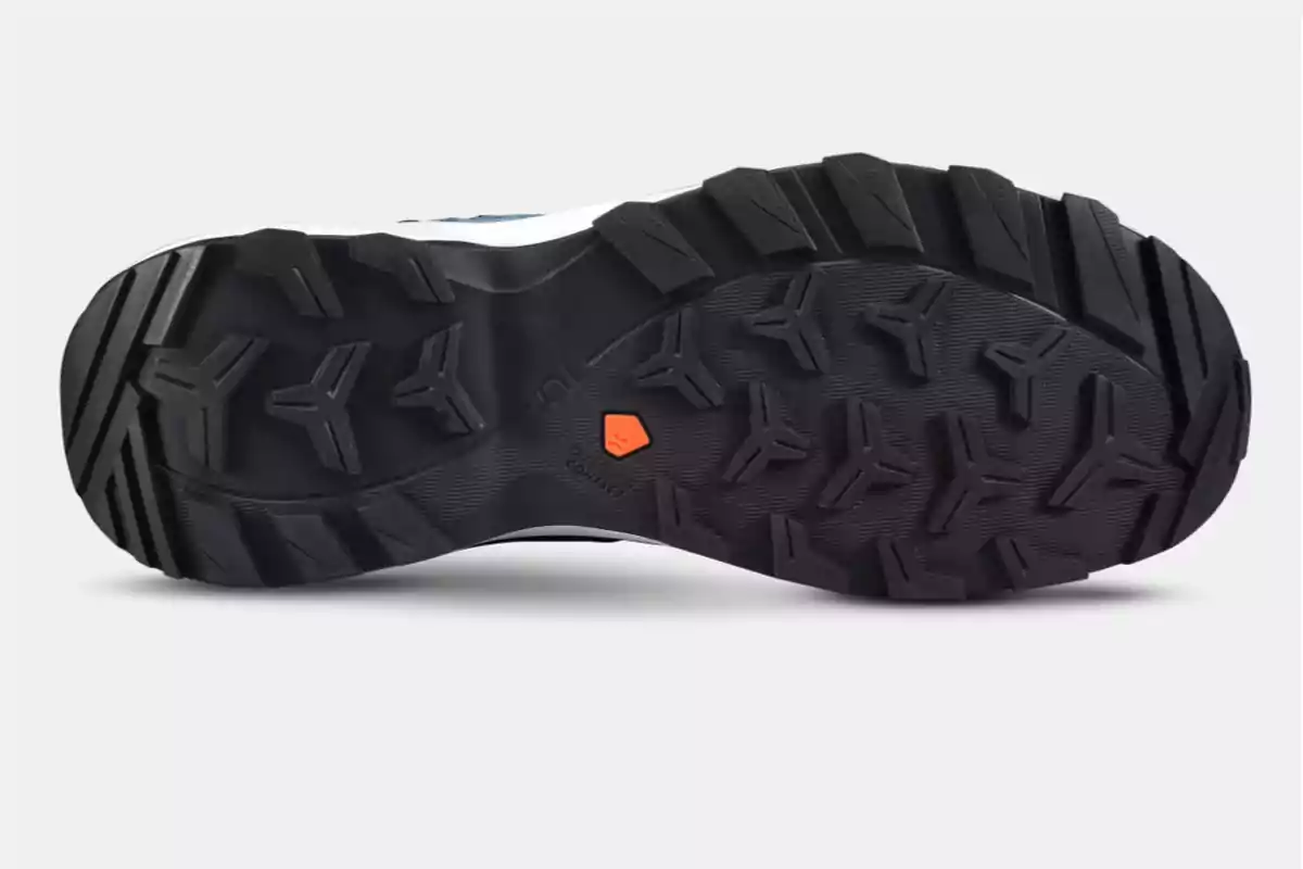 Suela de zapato deportivo con dibujo de tacos en forma de flecha y un pequeño detalle naranja Suela de zapato deportivo con dibujo de tacos en forma de flecha y un pequeño detalle naranja