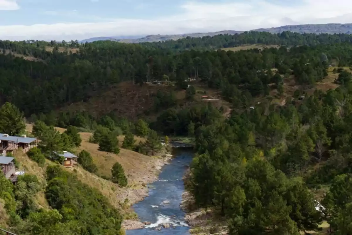 Vista panorámica de un río rodeado de árboles y cabañas en una zona montañosa Vista panorámica de un río rodeado de árboles y cabañas en una zona montañosa