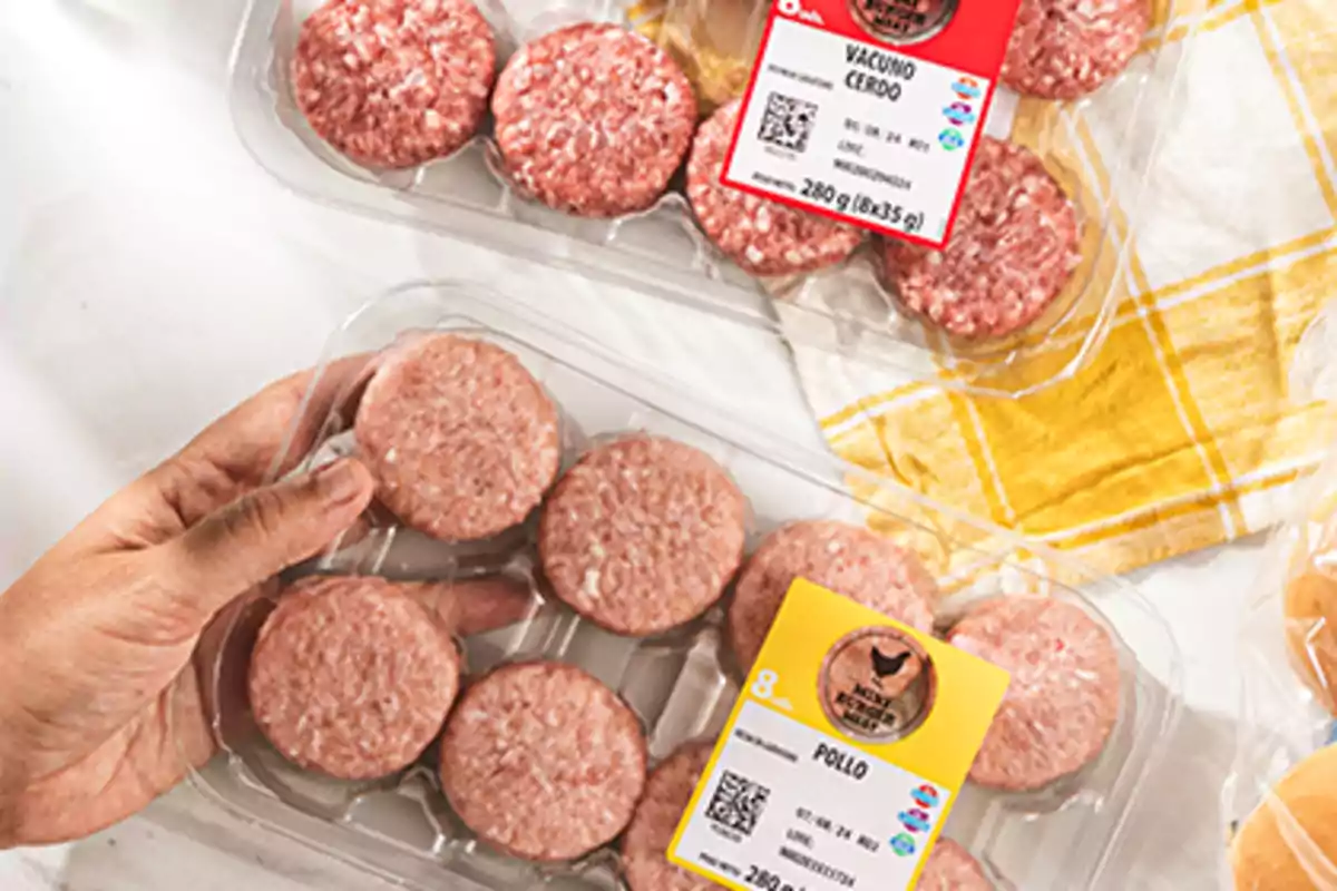 Bandejas de mini hamburguesas de pollo y de vacuno con cerdo en envases de plástico sobre una mesa con mantel amarillo Bandejas de mini hamburguesas de pollo y de vacuno con cerdo en envases de plástico sobre una mesa con mantel amarillo