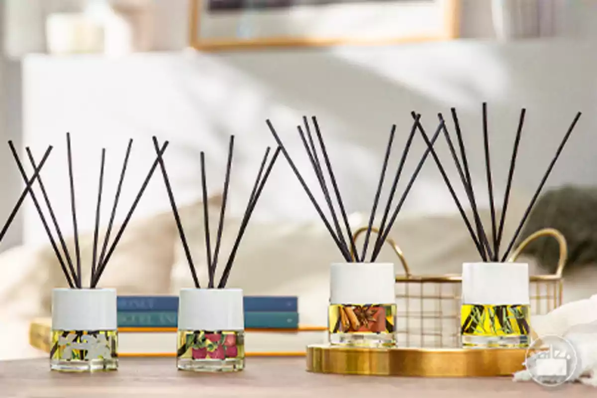 Cuatro difusores de varillas con líquidos aromáticos y decoraciones en su interior sobre una mesa en un ambiente hogareño iluminado Cuatro difusores de varillas con líquidos aromáticos y decoraciones en su interior sobre una mesa en un ambiente hogareño iluminado