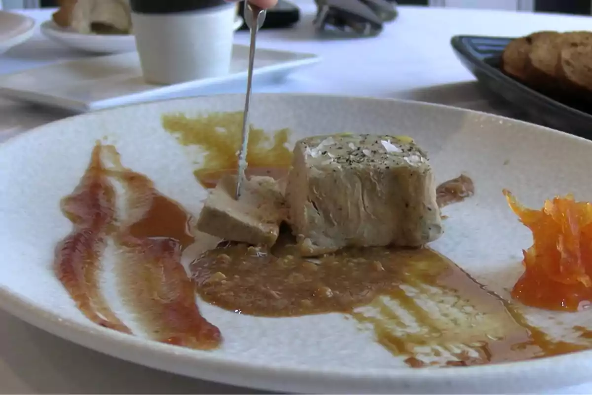 Plato gourmet con foie gras acompañado de salsas y una guarnición de zanahoria rallada