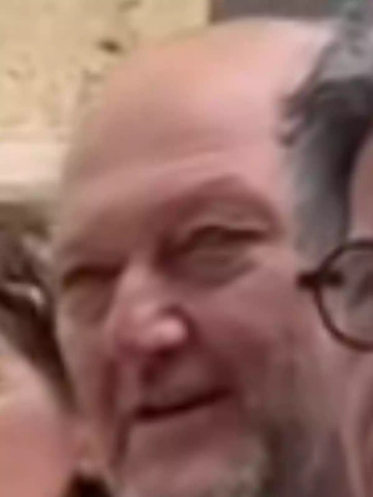 Hombre mayor calvo con barba corta y expresión sonriente en un entorno exterior desenfocado Hombre mayor calvo con barba corta y expresión sonriente en un entorno exterior desenfocado