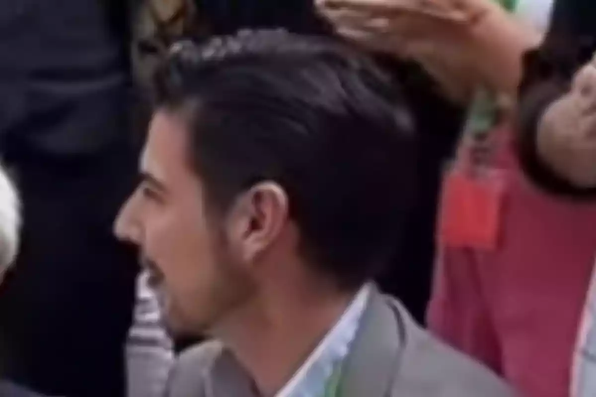 Hombre de perfil con cabello oscuro y barba corta en un entorno concurrido Hombre de perfil con cabello oscuro y barba corta en un entorno concurrido
