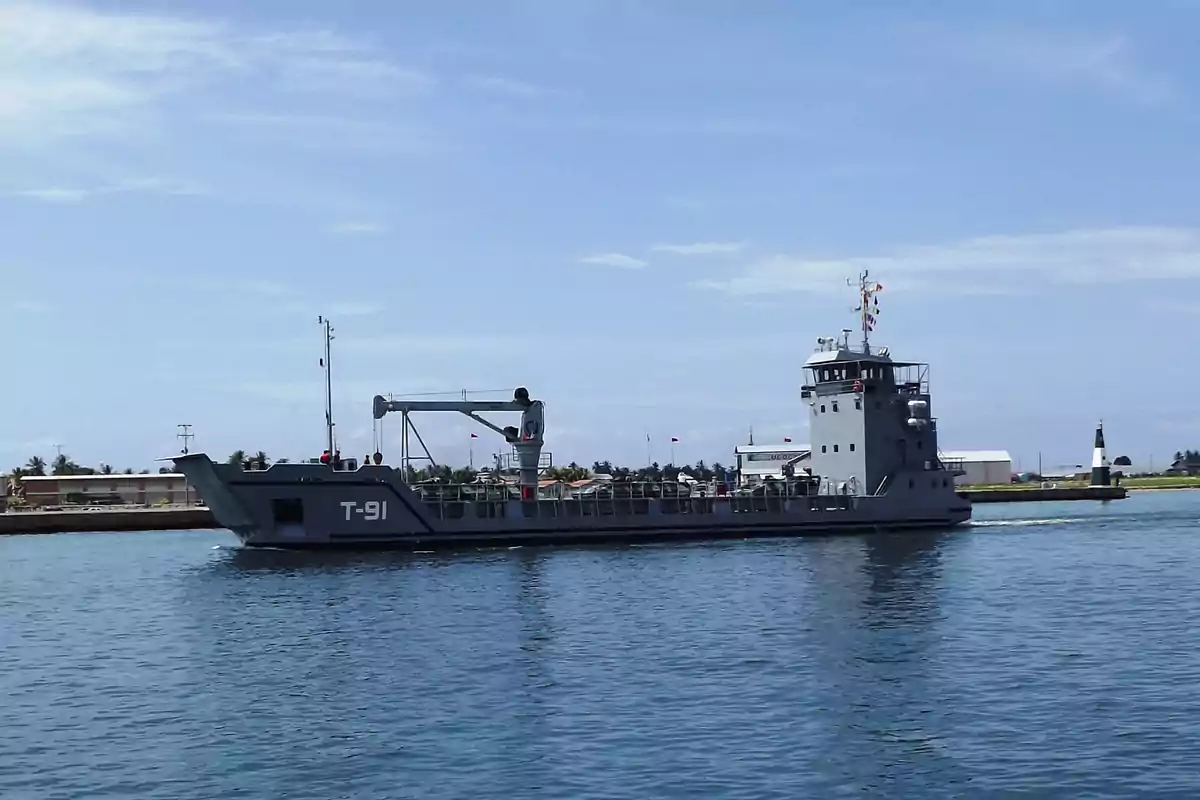 Barco gris militar navegando cerca de la costa en un día soleado Barco gris militar navegando cerca de la costa en un día soleado