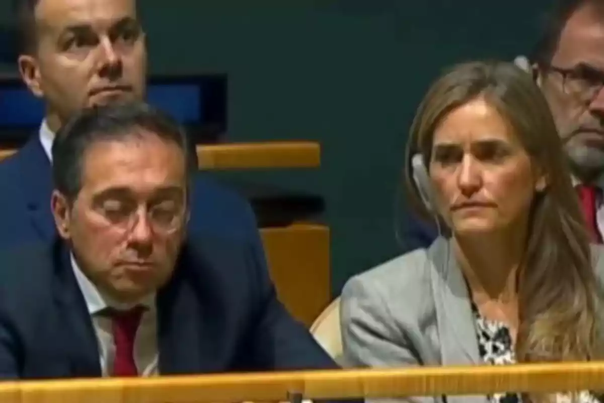 Personas sentadas en un auditorio con expresiones serias y formales