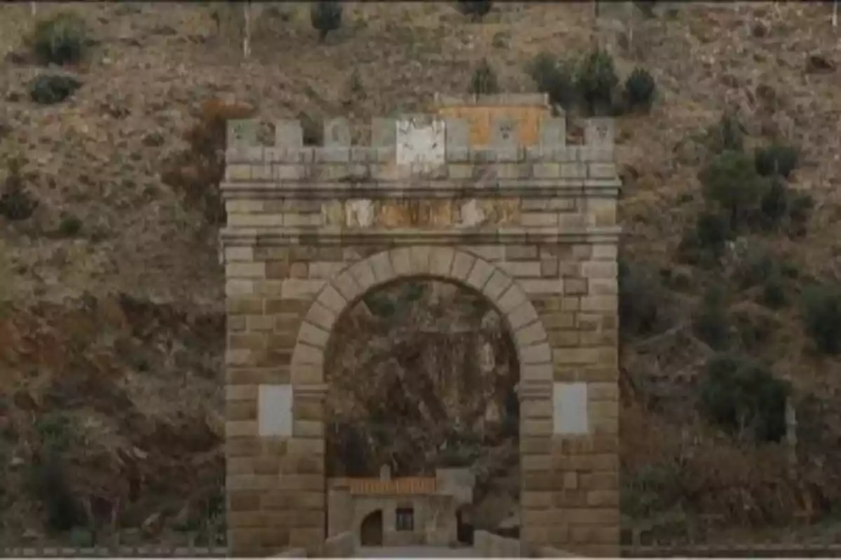 Arco de piedra antiguo en un entorno montañoso con vegetación dispersa Arco de piedra antiguo en un entorno montañoso con vegetación dispersa