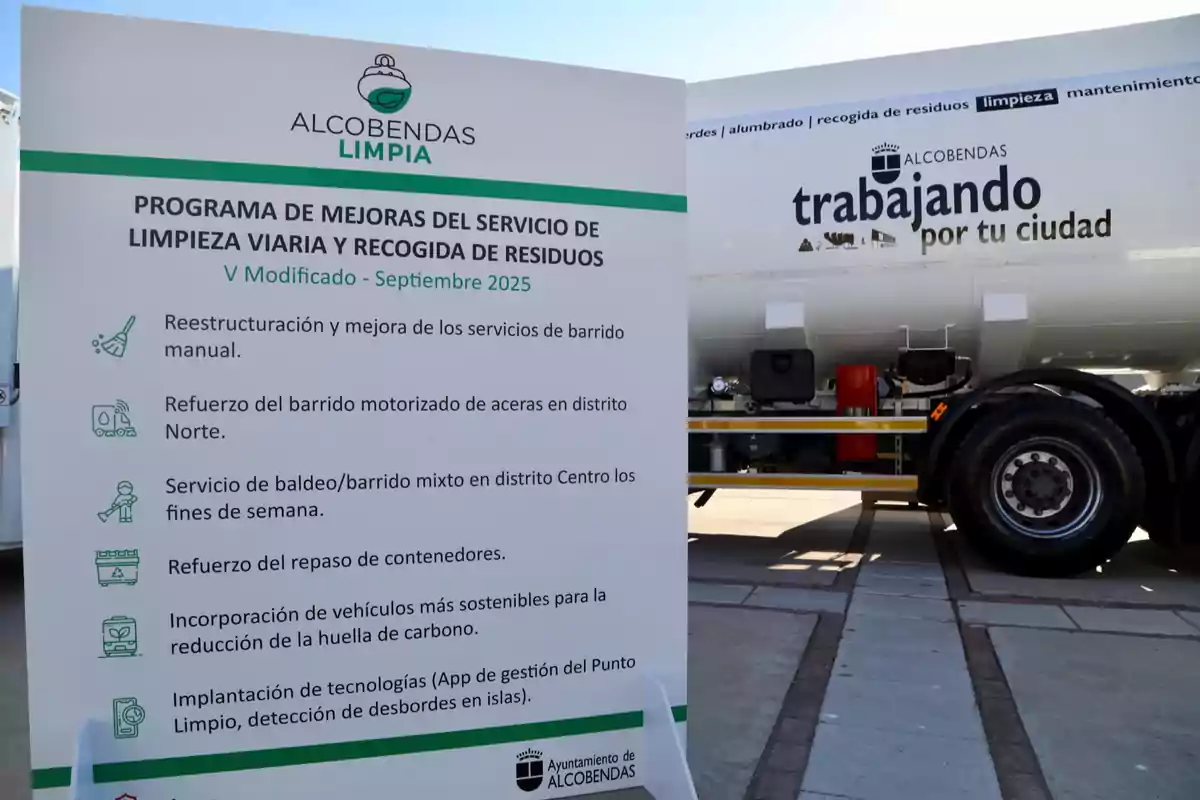 Cartel informativo del programa de mejoras del servicio de limpieza viaria y recogida de residuos en Alcobendas junto a un camión de limpieza con el lema trabajando por tu ciudad