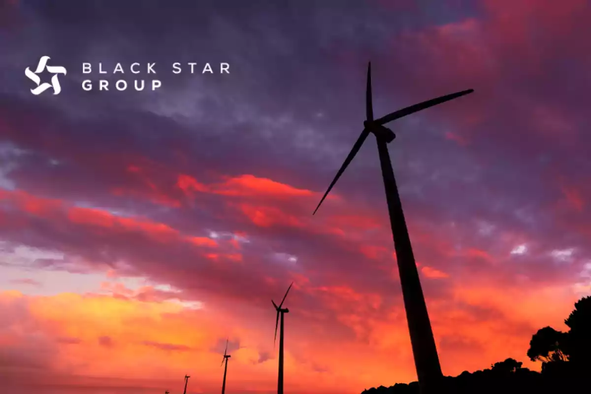 Aerogeneradores en silueta al atardecer con un cielo colorido y el logotipo de Black Star Group en la esquina superior izquierda