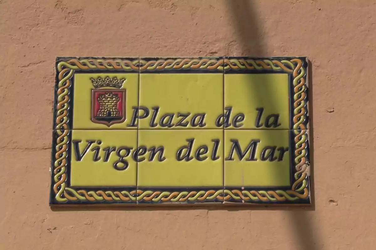 Placa de cerámica amarilla con borde decorativo que indica Plaza de la Virgen del Mar y un escudo en la esquina superior izquierda Placa de cerámica amarilla con borde decorativo que indica Plaza de la Virgen del Mar y un escudo en la esquina superior izquierda