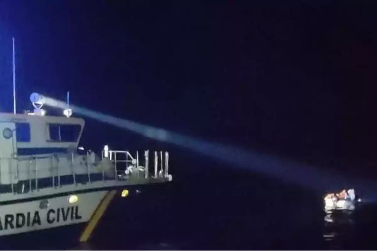 Una patrullera de la Guardia Civil ilumina con un foco una pequeña embarcación en el mar durante la noche Una patrullera de la Guardia Civil ilumina con un foco una pequeña embarcación en el mar durante la noche