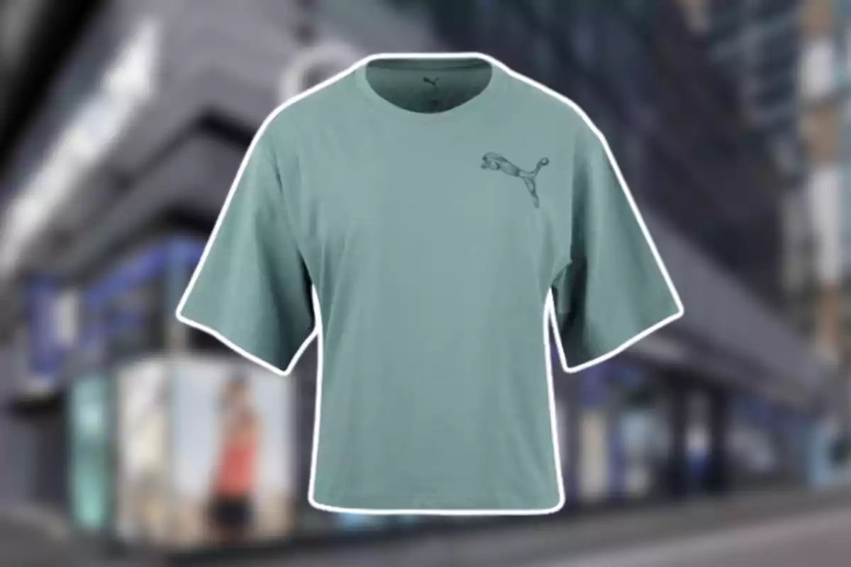 Camiseta verde de manga corta con el logo de Puma en el pecho sobre un fondo urbano desenfocado