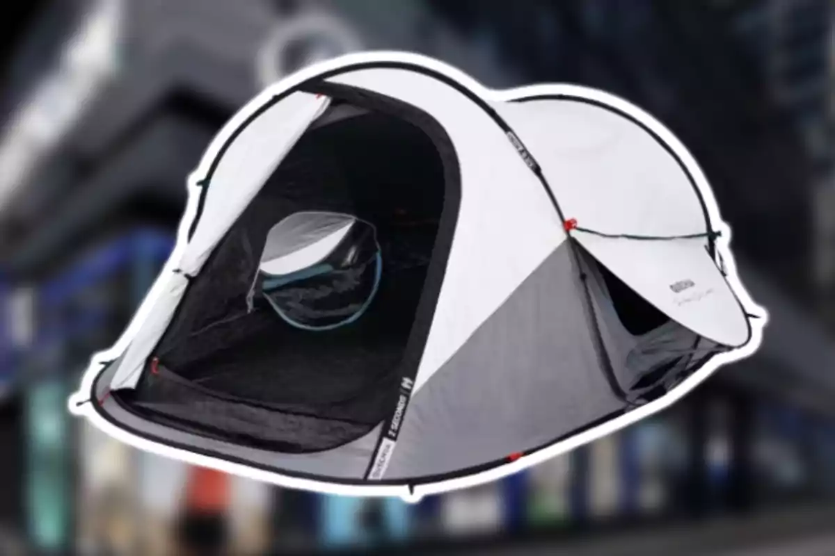 Tienda de campaña gris y blanca con la puerta abierta sobre un fondo urbano desenfocado