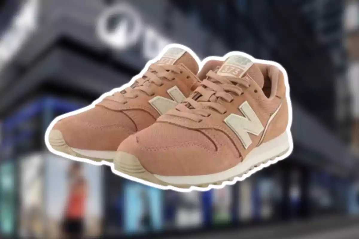 Zapatillas deportivas color beige de la marca New Balance modelo 373 sobre un fondo desenfocado de tienda