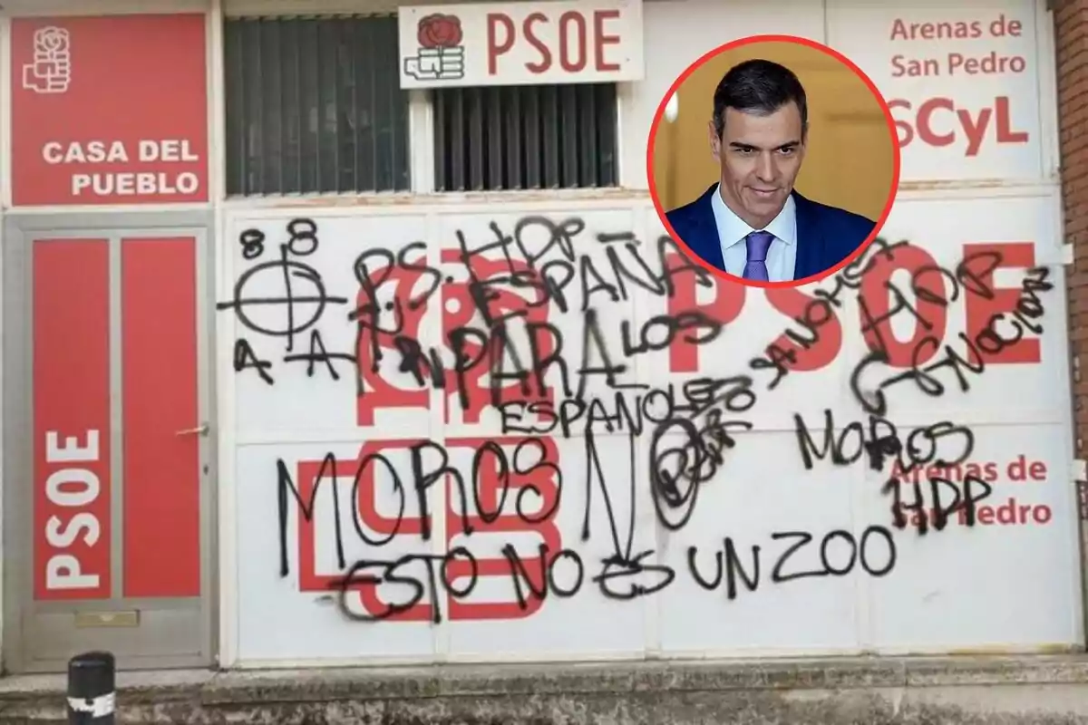 Fachada de una sede del PSOE con pintadas ofensivas en negro y un retrato de un hombre en un círculo rojo en la parte superior derecha