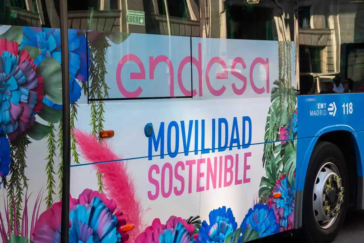 Autobús azul decorado con flores de colores y el mensaje movilidad sostenible junto al logo de Endesa