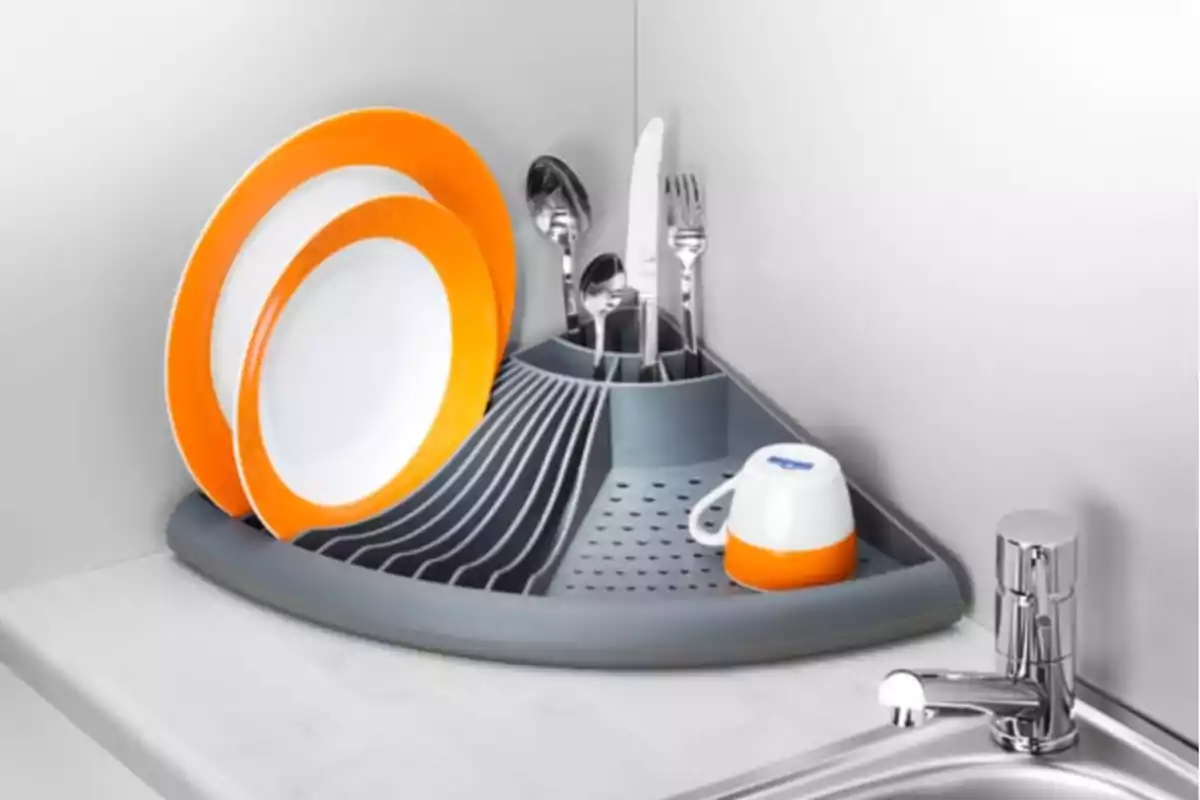 Escurridor de platos esquinero de color gris con platos, cubiertos y una taza junto a un fregadero moderno