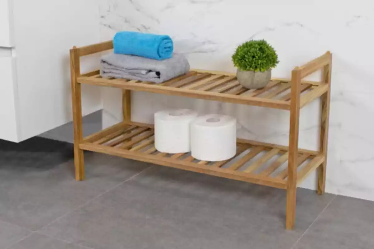 Estante de madera en baño con toallas, papel higiénico y una planta decorativa Estante de madera en baño con toallas, papel higiénico y una planta decorativa