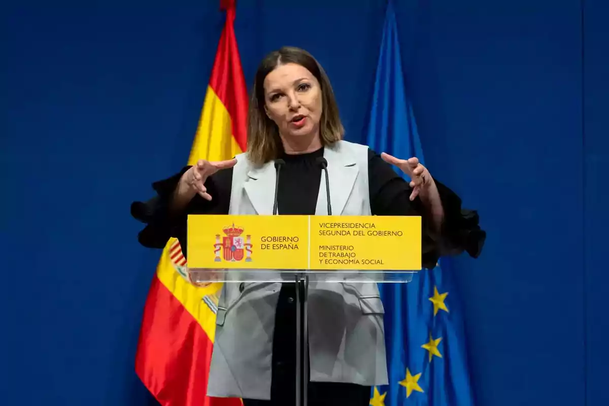 Mujer hablando en una rueda de prensa frente a un atril del Gobierno de España con las banderas de España y la Unión Europea de fondo Mujer hablando en una rueda de prensa frente a un atril del Gobierno de España con las banderas de España y la Unión Europea de fondo