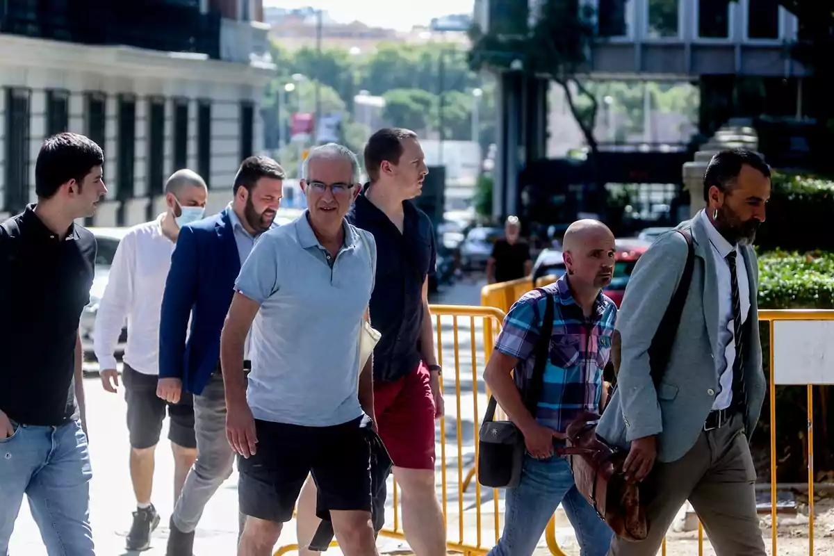 Un grupo de hombres camina por la acera en una ciudad en un día soleado
