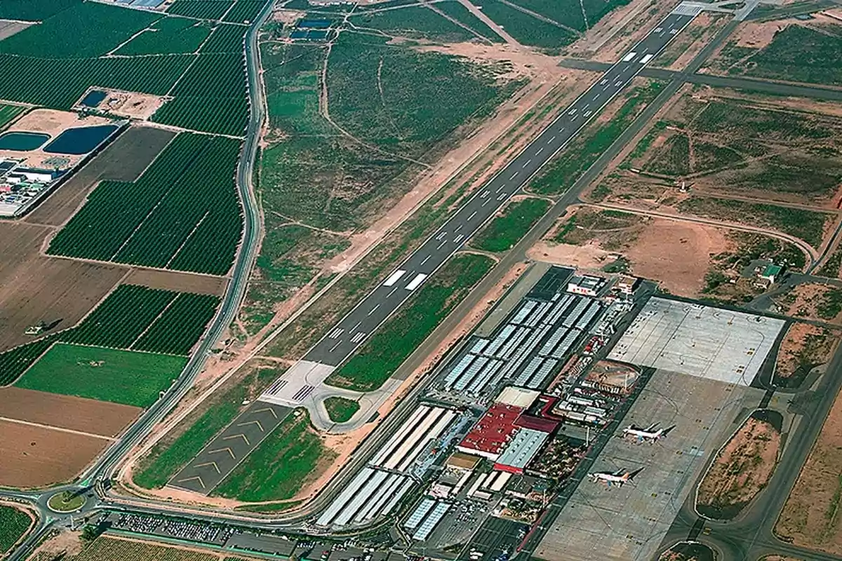 Vista aérea de un aeropuerto con una pista de aterrizaje, terminales, aviones estacionados y áreas agrícolas alrededor Vista aérea de un aeropuerto con una pista de aterrizaje, terminales, aviones estacionados y áreas agrícolas alrededor