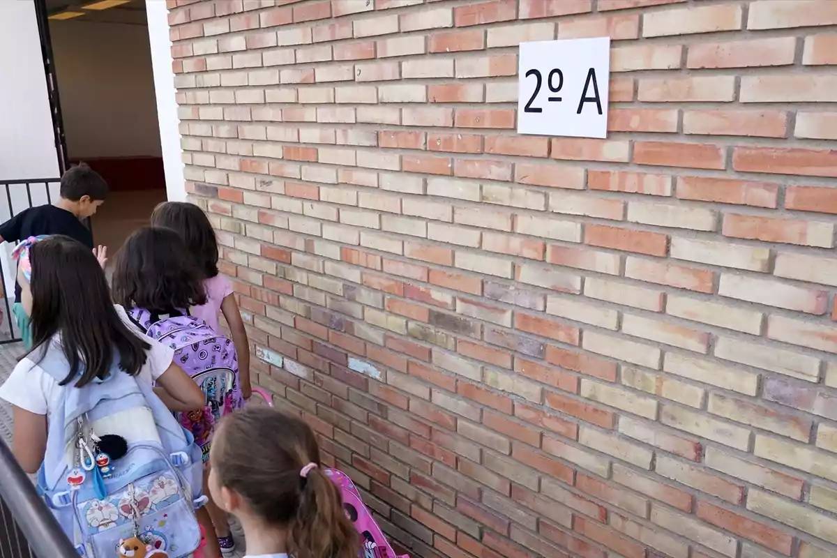 Niños con mochilas entrando en fila a un aula identificada como 2º A en una escuela Niños con mochilas entrando en fila a un aula identificada como 2º A en una escuela