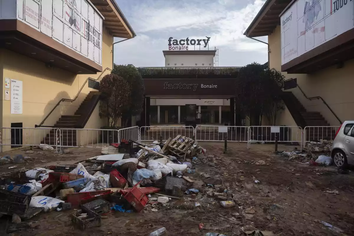 Entrada de un centro comercial con basura y escombros en el suelo y un ambiente de suciedad