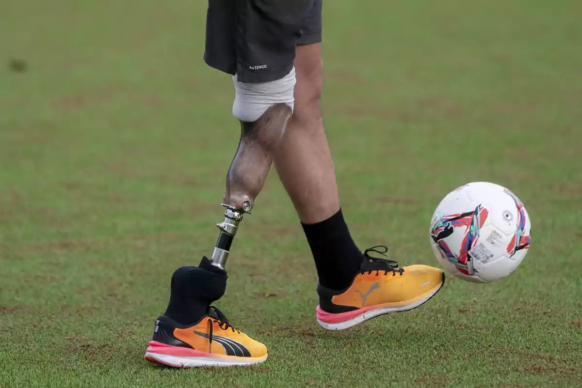 Persona con prótesis en la pierna jugando fútbol en un campo de pasto