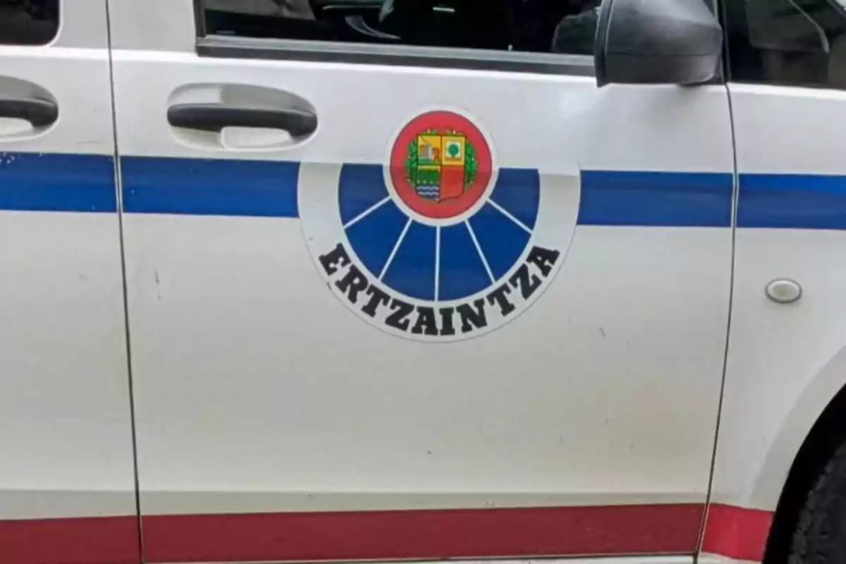 Puerta de un vehículo policial blanco con una franja azul y el escudo de la Ertzaintza Puerta de un vehículo policial blanco con una franja azul y el escudo de la Ertzaintza