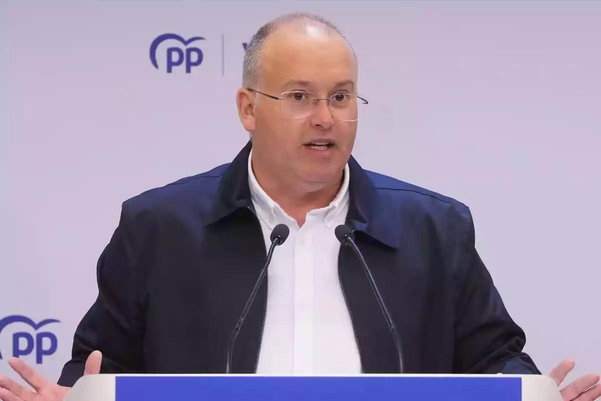 Hombre con gafas y chaqueta oscura hablando en una rueda de prensa frente a un atril con el logotipo del PP al fondo Hombre con gafas y chaqueta oscura hablando en una rueda de prensa frente a un atril con el logotipo del PP al fondo