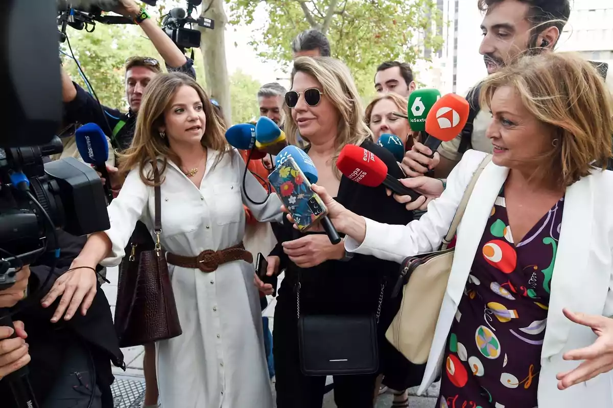 Un grupo de periodistas rodea a una mujer mientras le hacen preguntas y la graban con micrófonos y cámaras en la calle